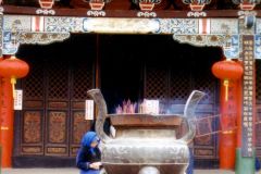 China - Kunming - The expression of religion has in China over the last few years been subject to liberalisation. The old shrines and temples are again being visited by worshippers, even though it is first of all the elderly who are most active. These two women are praying in a Buddhist temple after having placed their incense in the sand.