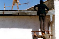 China - Tibet - Lhasa - Progress to the people: Helping Chinese locals setting up a TV antenna. The owners of the hotel had taken the step into civilisation. They had bought a TV set. The aerial they had made themselves by twisting some iron rods. An Aussie and I helped them fix it to the roof and plug the chord into the TV – and it worked. There was much ado in the family, and we were treated with beers and lots of sweets.
